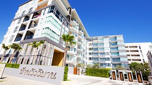 Un hotel moderno de varios pisos con una entrada destacada, balcones y cielo despejado.