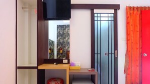 Ein Zimmer mit einem Holztisch, einem kleinen Hocker, einem roten Vorhang und einer Tür mit einem Metallgitter.
