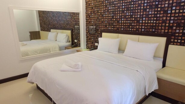 Ein Hotelzimmer mit einem großen Bett, einem Spiegel und einer Wand mit Muster.