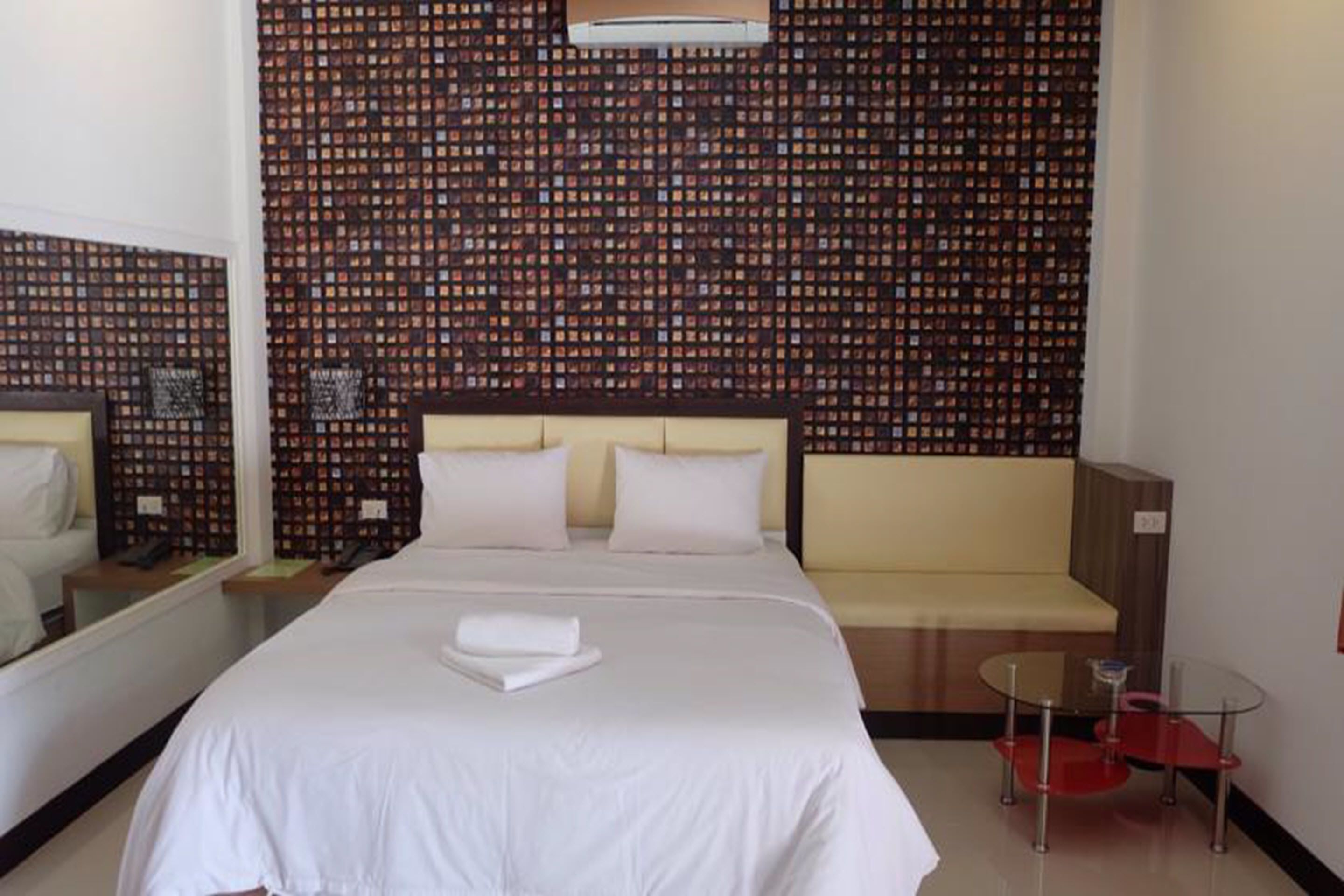 Una habitación de hotel con una cama grande, un sofá, una mesita y un espejo.