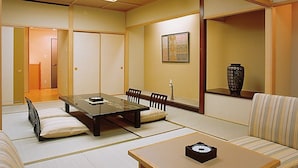 Una habitación tradicional japonesa con suelo de tatami, una mesa baja con un reloj y un sofá.