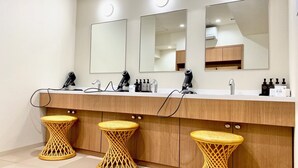 Un baño moderno con tres espejos, un lavabo y tres taburetes de mimbre.