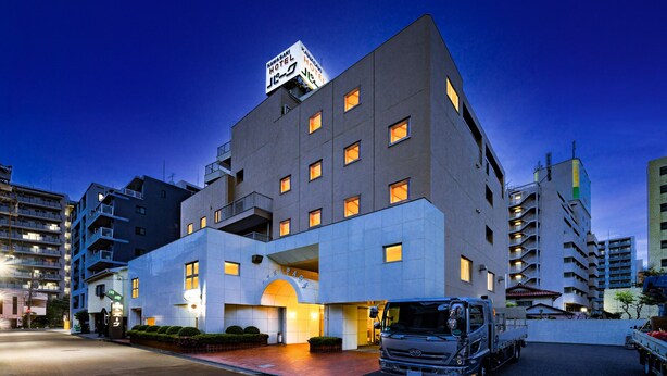 Un hotel moderno con un letrero llamativo, varios balcones y una entrada bien iluminada.