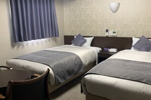 Une chambre d’hôtel avec deux lits, un bureau et une chaise.