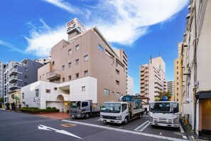 Un hotel de varios pisos con un letrero llamativo, varios camiones estacionados y un cielo azul despejado.