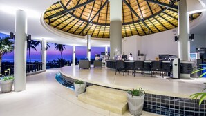 Un vaste espace intérieur doté d’un haut plafond, d’un bar central et d’une piscine.