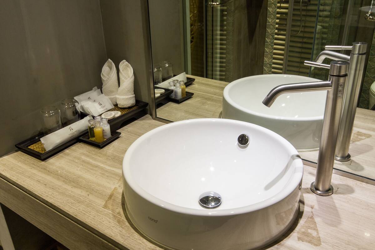 Une salle de bain moderne avec un grand lavabo blanc, un miroir et un porte-serviettes.