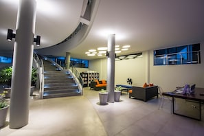 A modern lobby with a staircase, seating areas, and a reception desk. - Villa By The Tarna (Koh Tao)