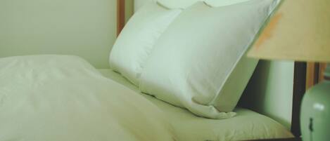 A bed with white bedding and a lamp on a bedside table.