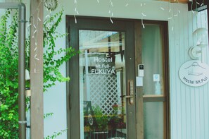 La entrada al Hostal Mt.Fuji-Ekuyama, con una puerta de madera, un ventanal y un letrero que indica el nombre del hostal.