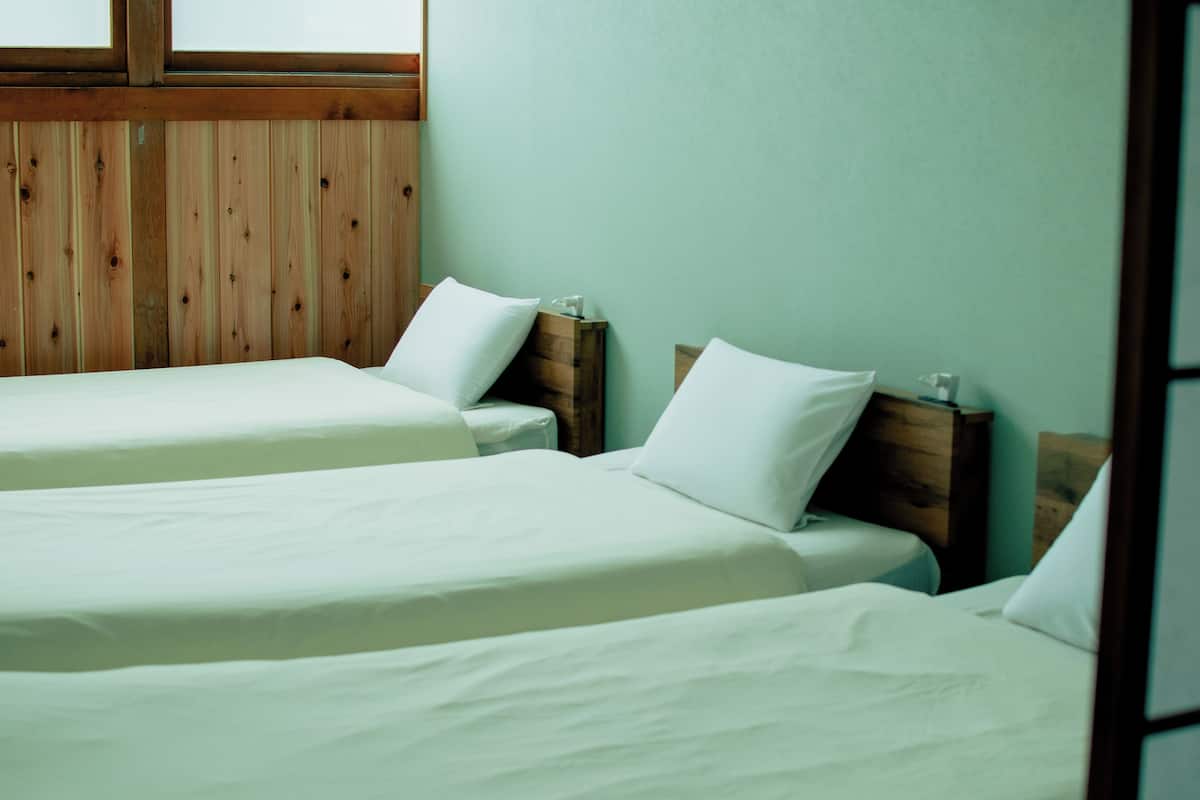 A room with two single beds, wooden headboards, and a light green wall.