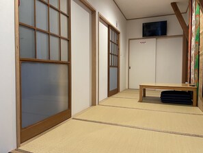 Un pasillo con suelo de tatami, puertas correderas y un televisor montado en la pared.