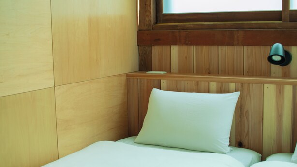 A small, single-bed room with wooden panel walls and a window. - Hostel Mt. Fuji-FUKUYA (Fujiyoshida)