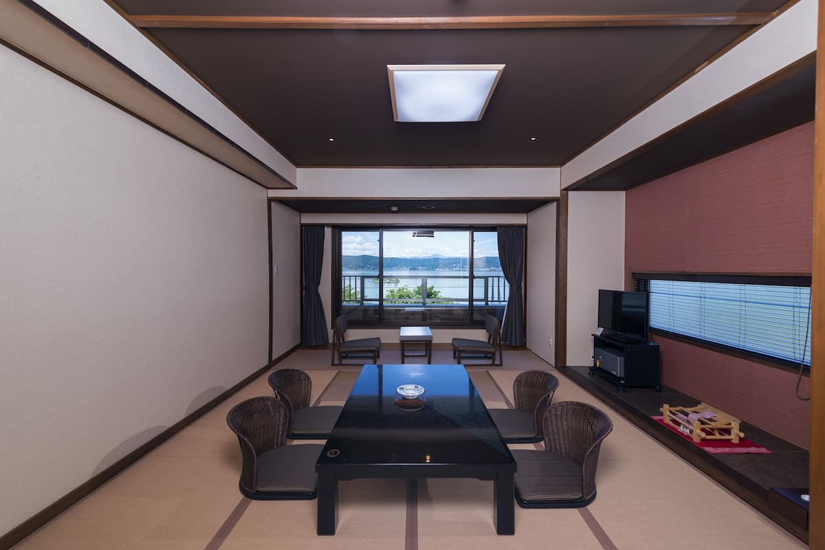 A modern room with a large table, chairs, a television, and a view of the outdoors.