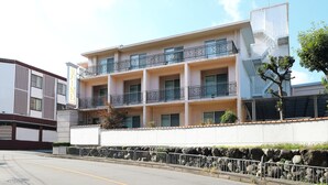 A multi-story building with balconies, a stone wall, and a clear sky. - Hotel Olive Kyoto Yamashina - Adults Only (Kyoto)