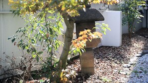 A stone lantern in a garden with a white wall and gravel path. - Hotel Olive Kyoto Yamashina - Adults Only (Kyoto)