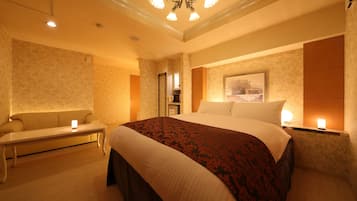 A hotel room with a large bed, a bench, a desk, and a chandelier.