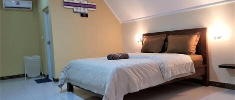 A bedroom with a bed, a wall-mounted air conditioner, and a small table.