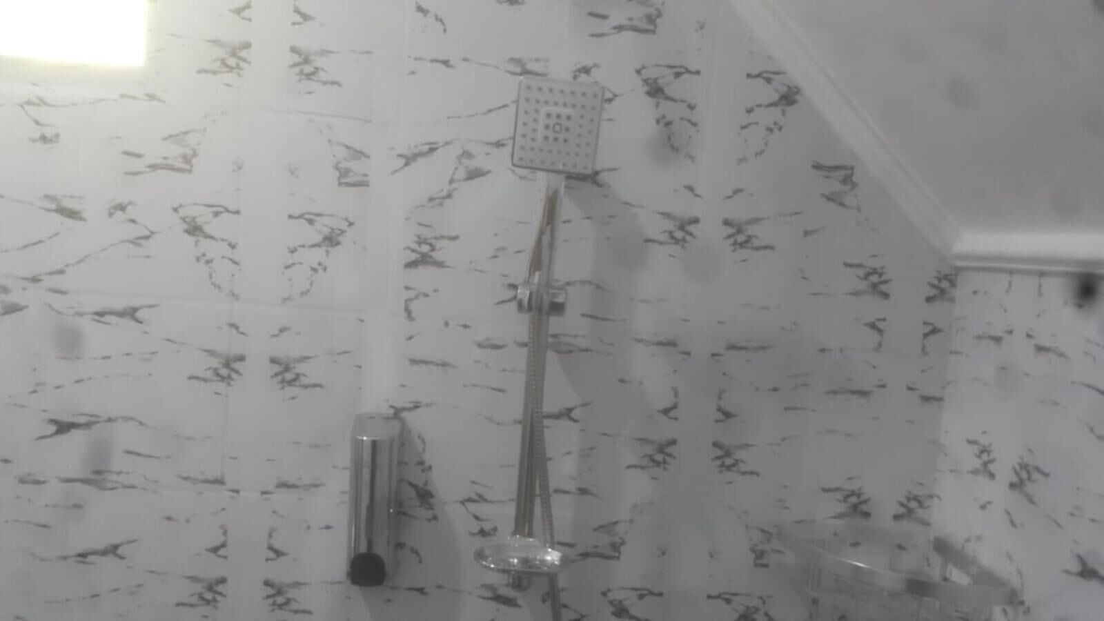 A shower with a handheld showerhead and a wall-mounted faucet.