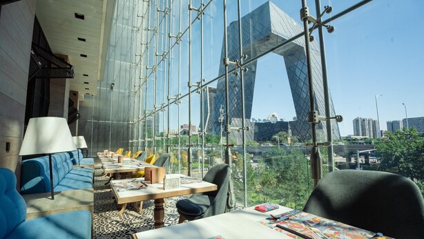 A modern interior with a glass wall, seating, and tables.