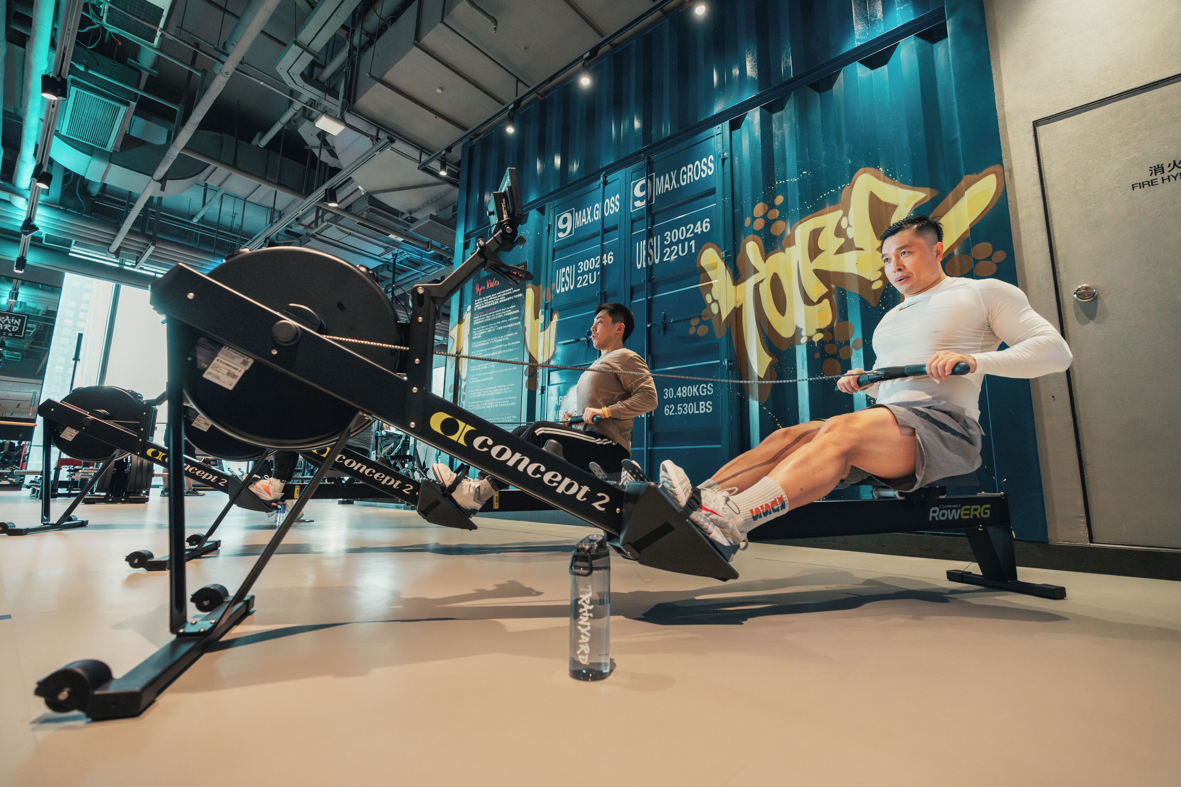 Ein Rudergerät in einem Fitnessstudio, auf dem Boden steht eine Wasserflasche.