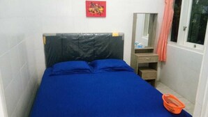 A small, neatly arranged bedroom with a single bed, a nightstand, a mirror, and a window with a curtain. - Bromo Sunrise Homestay (Probolinggo)