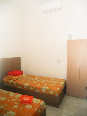 A small room with two single beds, a wooden wardrobe, and a wall-mounted air conditioner. - Bromo Sunrise Homestay (Probolinggo)