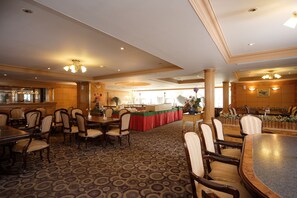 A spacious dining area with multiple tables and chairs, a central buffet table, and a patterned carpet. - Noble Hotel (Kaohsiung)