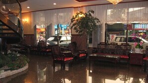 A lobby with a polished floor, a staircase, and a seating area with chairs and tables. - Noble Hotel (Kaohsiung)