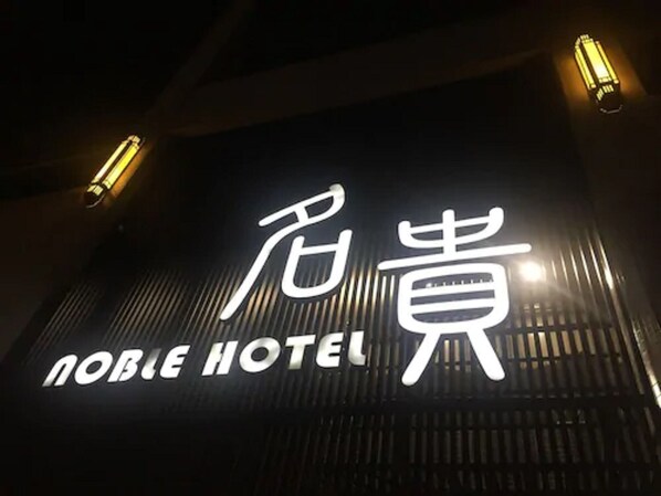 A hotel sign with illuminated text, including a name and a symbol. - Noble Hotel (Kaohsiung)