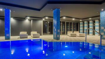 Alberca techada, alberca al aire libre y sombrillas en la alberca