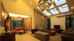 A modern living room with a sofa, coffee table, and TV, a dining area with a table and chairs, and a large window with curtains. - Country Garden Phoenix Hotel Jingmen (Jingmen)