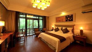 A hotel room with a large bed, a desk, and a chair. There is a window with curtains, a painting on the wall, and a ceiling light fixture. - Country Garden Phoenix Hotel Jingmen (Jingmen)