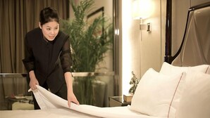 A hotel room with a neatly made bed, a bedside table with a lamp, and a view of a plant through the window. - Country Garden Phoenix Hotel Jingmen (Jingmen)