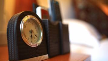 A clock with a dark, textured base and a white face, placed on a wooden surface.