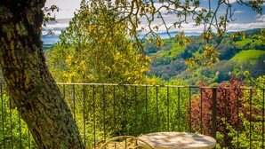 Juego de mesa y sillas metálicos al aire libre, con un árbol y vistas a un paisaje verde.