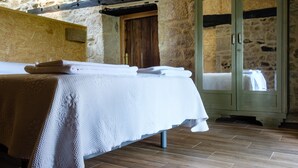 Una habitación con cama, un armario de madera y una pared de piedra.