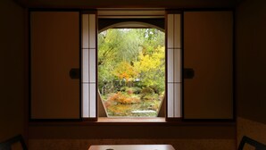 A traditional Japanese room with tatami flooring, a low table with two cups, and a view of a garden through a shoji screen. - Tachibanaya (Tsuruoka)