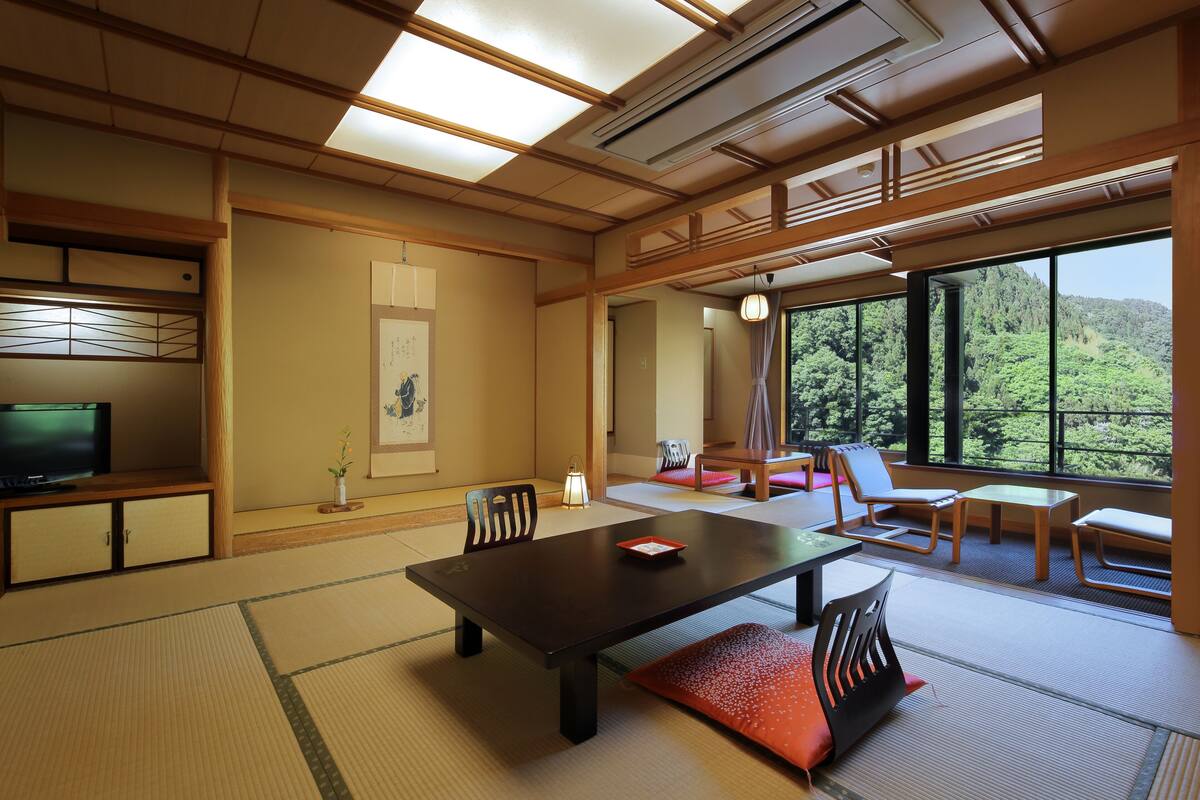 Ett traditionellt japanskt rum med tatamimattor på golvet, ett lågt bord, stolar och en tv.