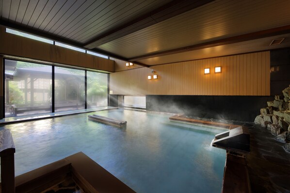 A modern indoor pool with clear glass walls, wooden paneling, and built-in lighting.