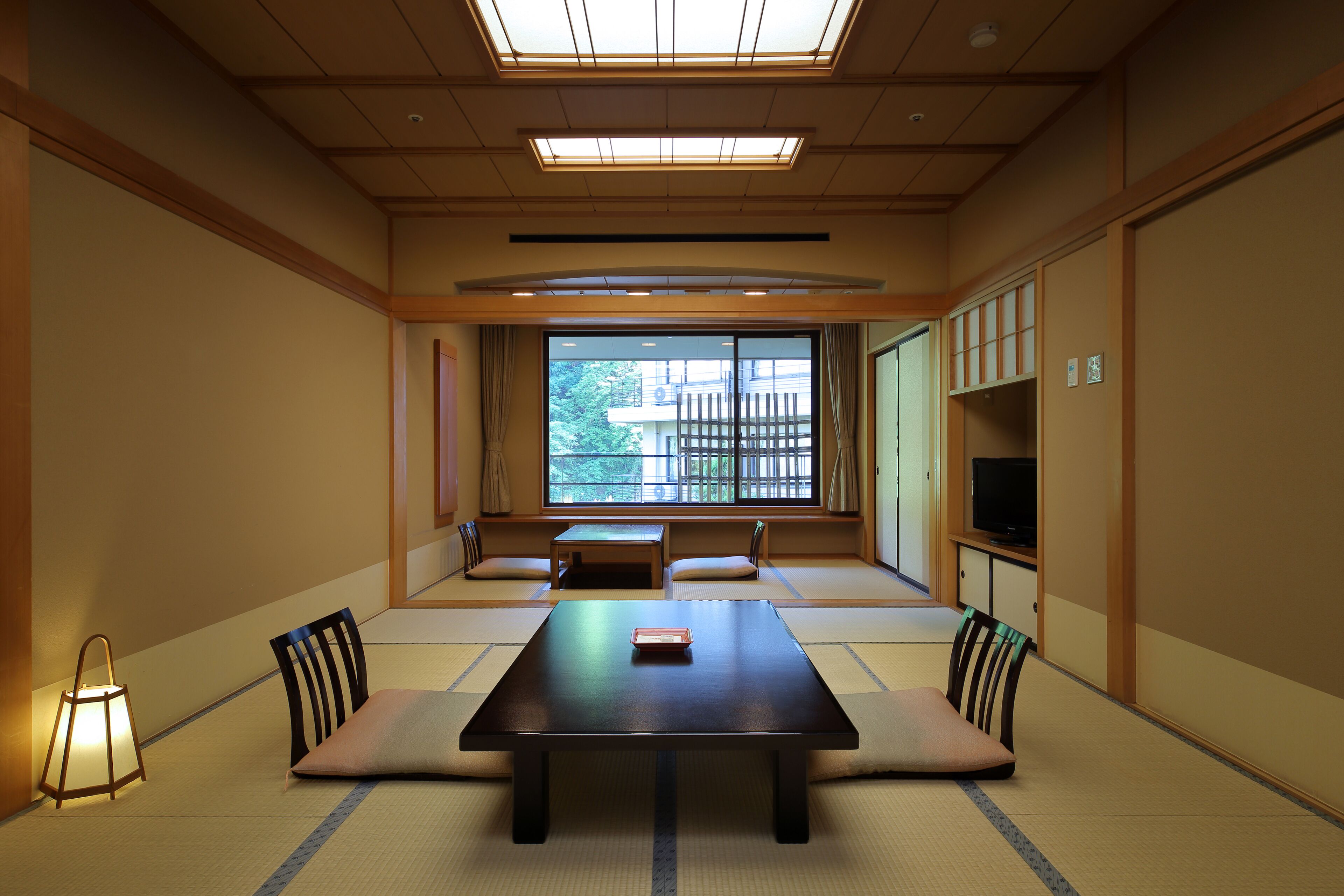 Una tradizionale stanza con tatami, un tavolino basso, cuscini e un televisore.