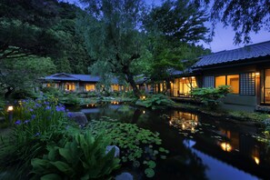 A traditional Japanese-style building with a koi pond and lush greenery.