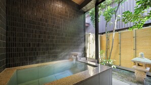 A modern spa area with a hot tub, tiled walls, and a stone lantern. - Tachibanaya (Tsuruoka)