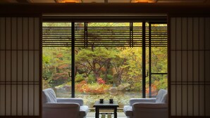 A traditional Japanese room with tatami flooring, a low table with tea set, and a view of a garden through shoji screens. - Tachibanaya (Tsuruoka)