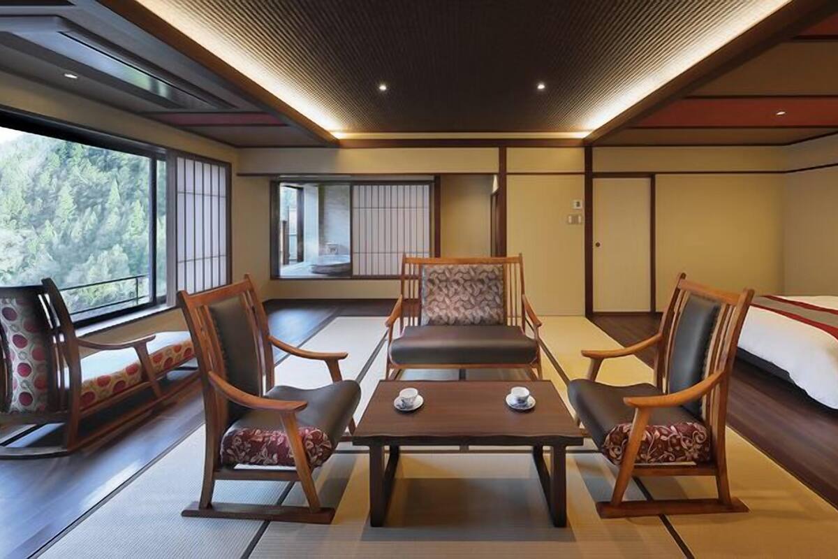 Ett traditionellt japanskt rum med tatamimattor på golvet, ett lågt bord med två koppar och en säng med en röd detalj.