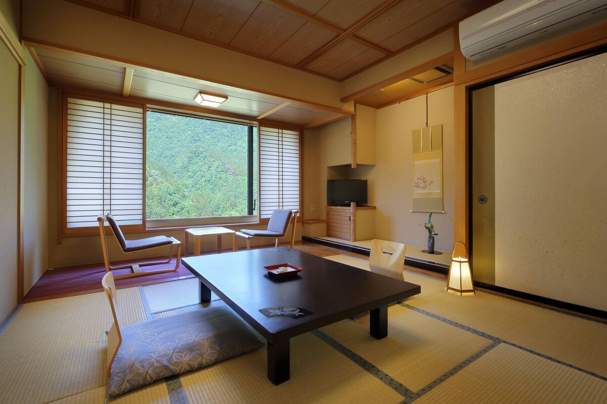 Ett traditionellt japanskt rum med tatamimattor på golvet, ett lågt bord och skjutdörrar.
