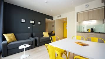 A modern living room with a grey sofa, yellow chairs, a white table, and a small white floor lamp.