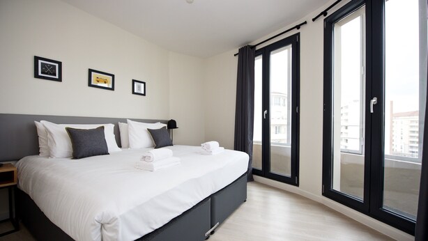 A modern hotel room with a large bed, a nightstand, and a view through a sliding door to an outdoor balcony. - Staycity Aparthotels, Lyon Rue Garibaldi (Lyon)