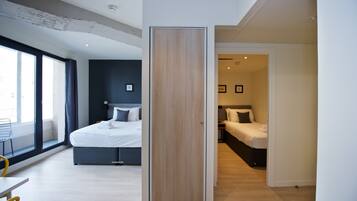 Een moderne hotelkamer met een groot bed, een afzonderlijke zithoek en uitzicht door een schuifdeur.