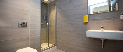 Une salle de bain moderne avec une douche à parois de verre, un lavabo blanc et des toilettes.